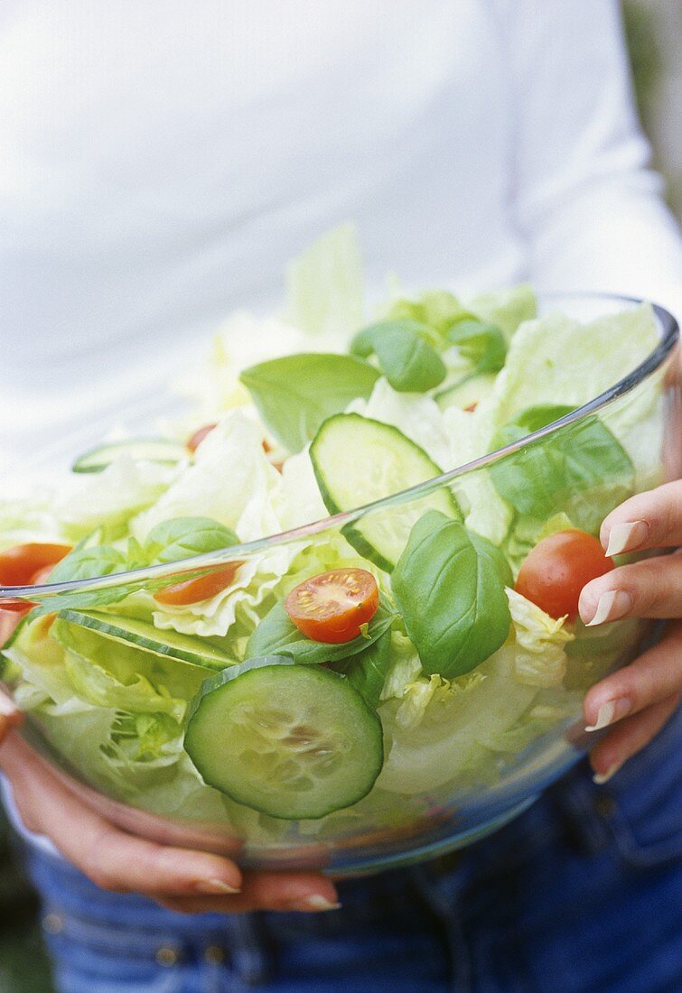 Frau hält Glasschüssel mit gemischtem Salat