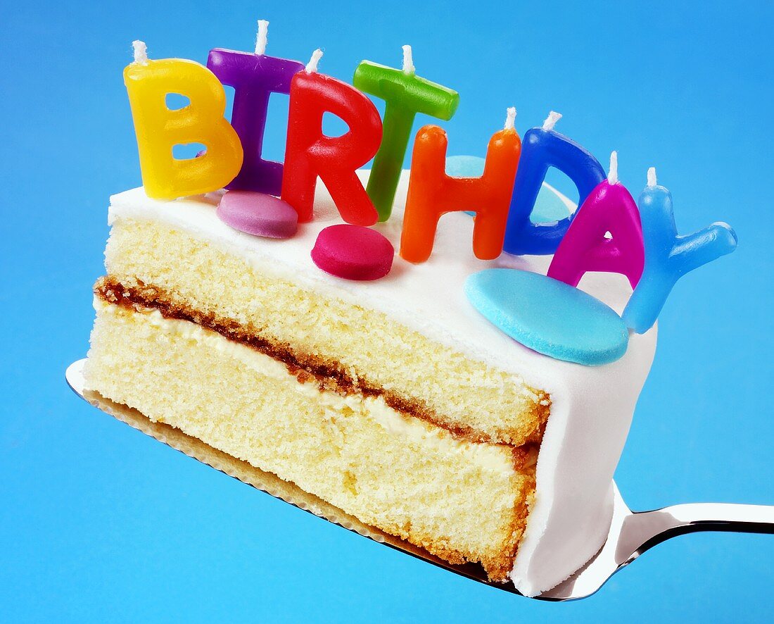 Ein Stück Geburtstagstorte mit Buchstaben-Kerzen: 'BIRTHDAY'