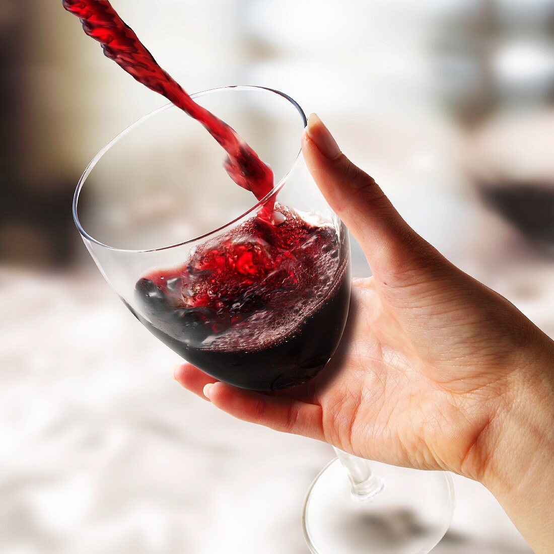 Rotwein in ein Glas gießen