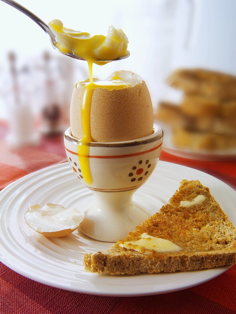 Boiled egg with spoon and toast triangle
