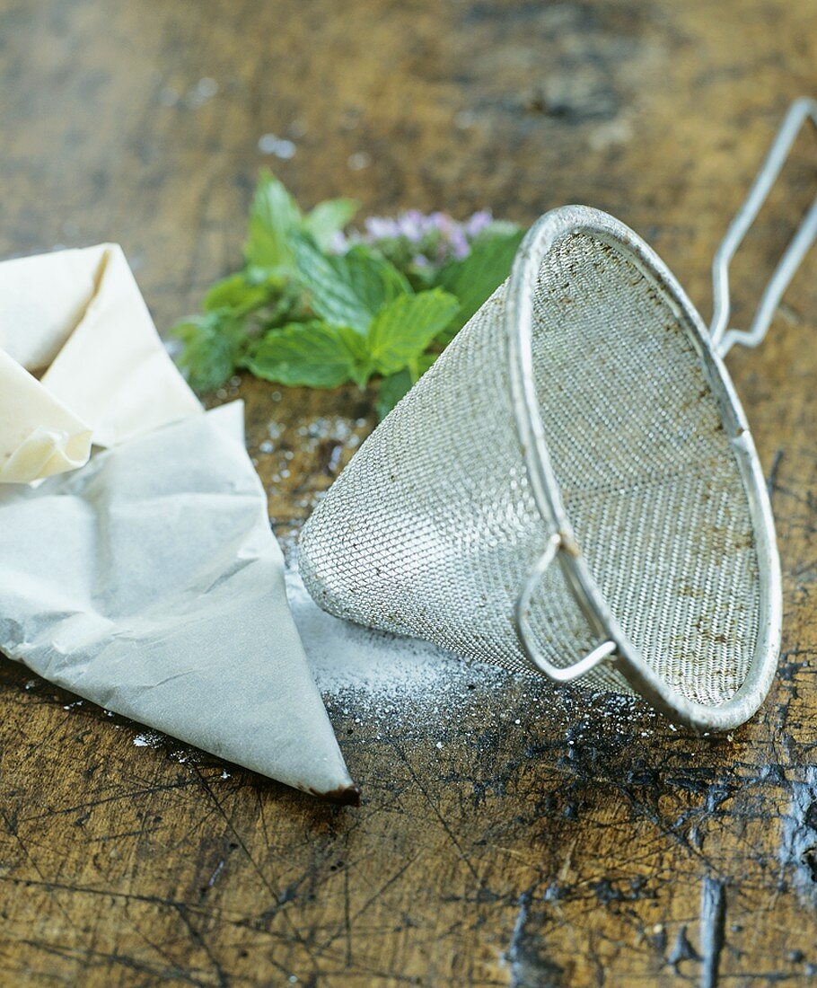 Sieve and sugar on wooden background