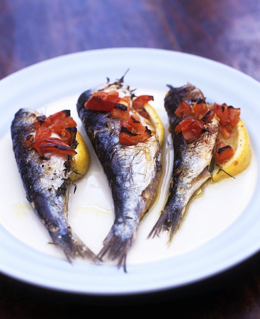 Grilled sardines with tomatoes and lemon wedges