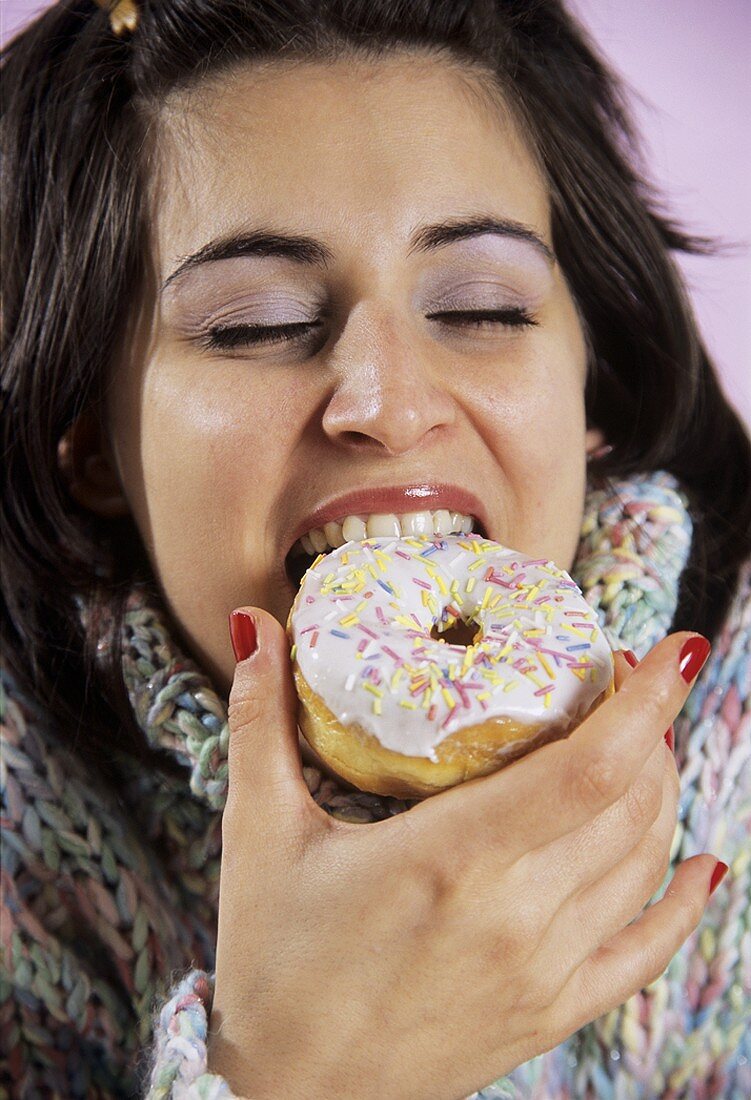 Young woman biting into a doughnut