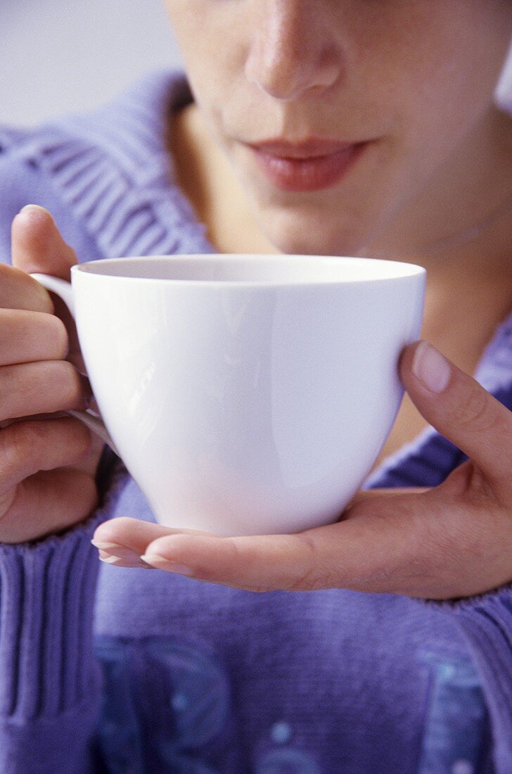 Junge Frau bläst in eine Tasse heißen Tee