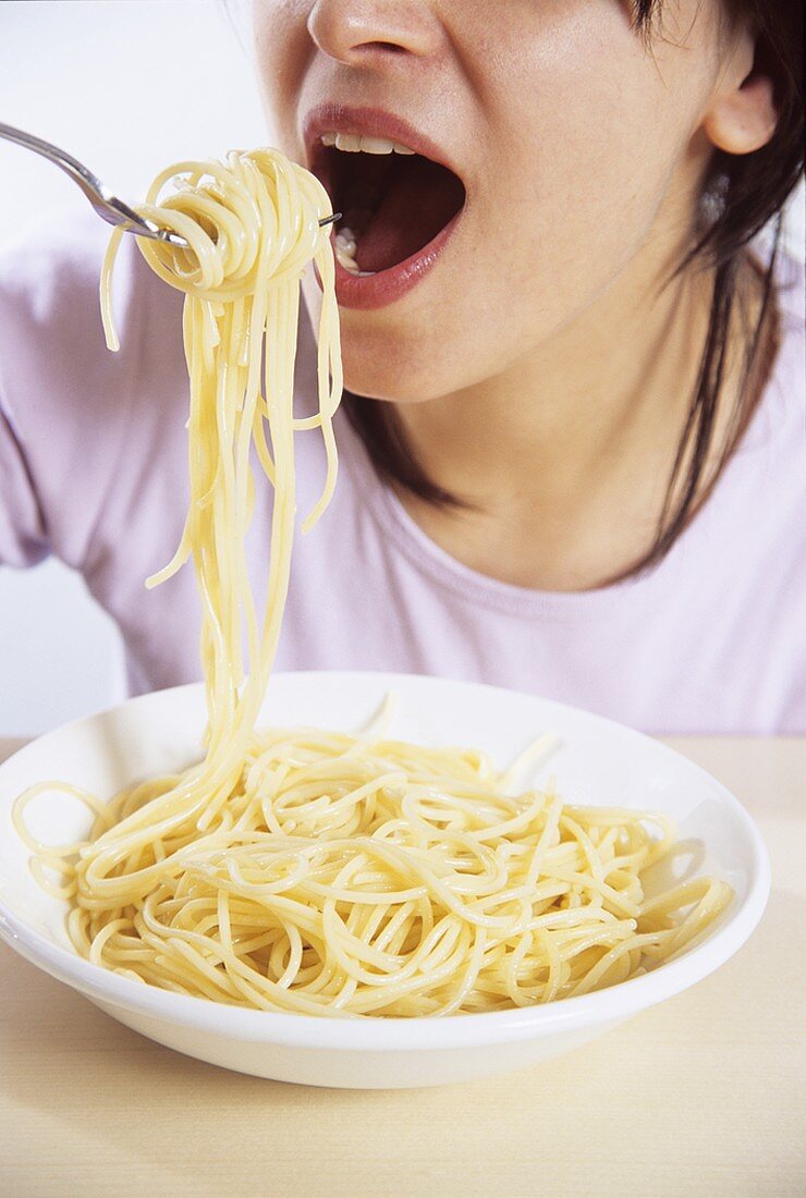 Young woman eating spaghetti