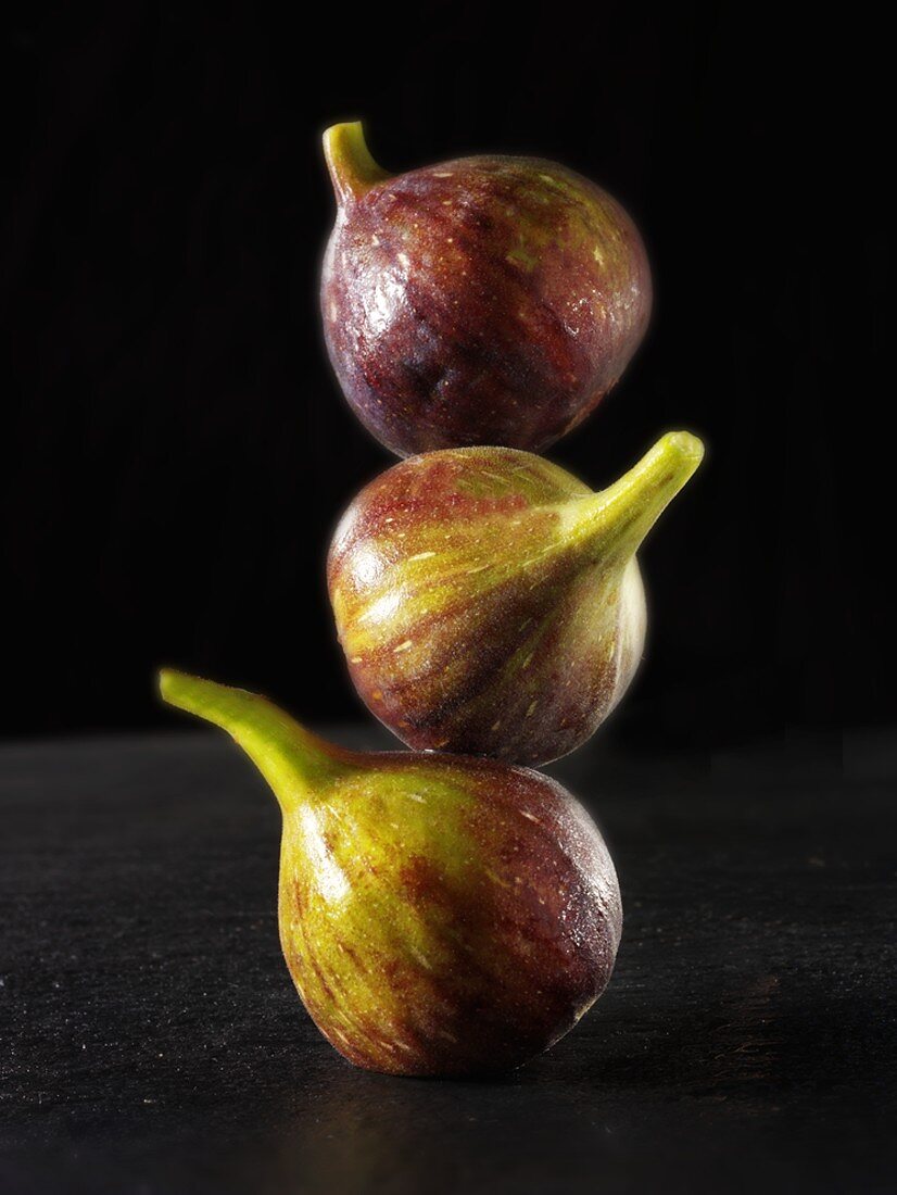 Three fresh figs, in a pile, one on top of the other