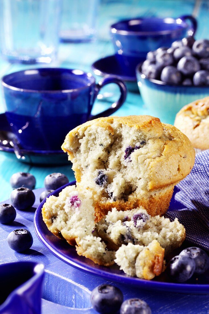 Blueberry muffin, blue coffee cups and fresh blueberries