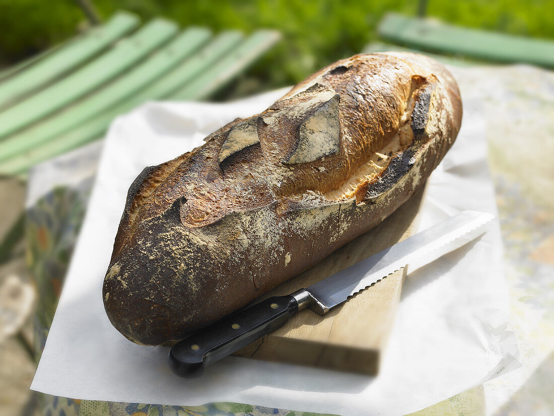 Brot mit Brotmesser auf einem Tisch im Garten
