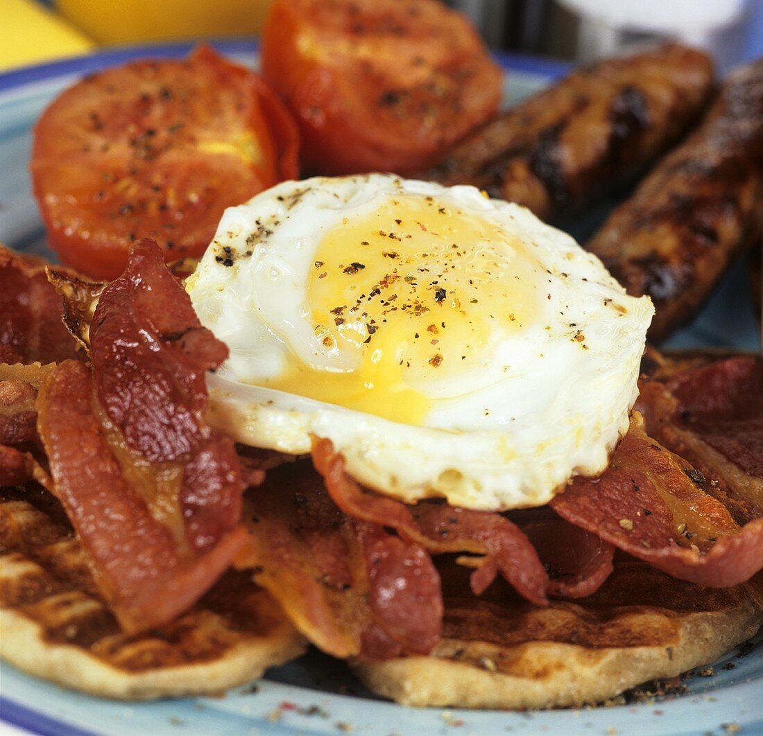 Englisches Frühstück mit Waffel, gebratenem Speck, Spiegelei