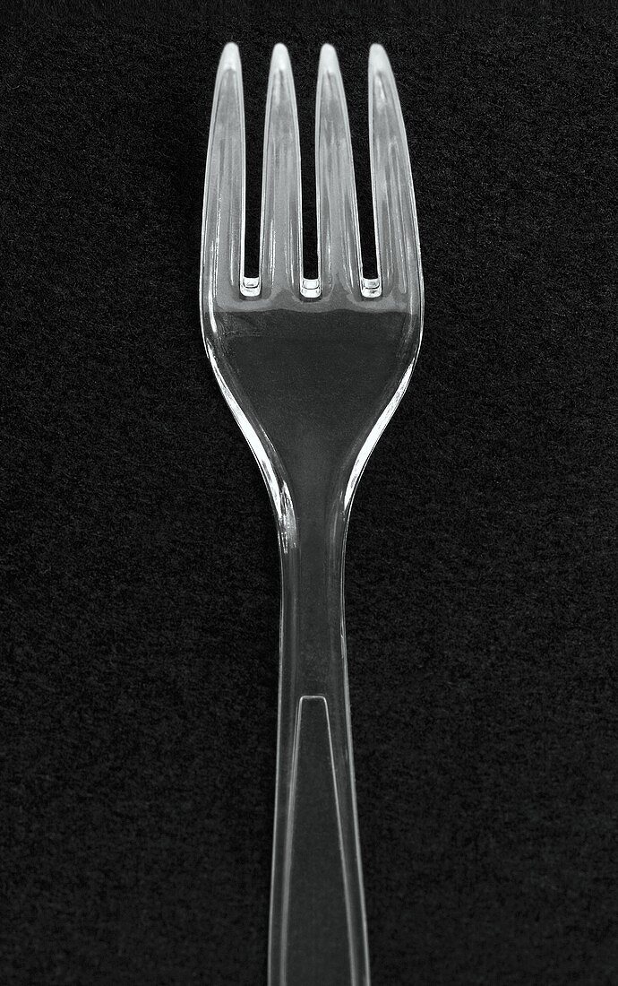 A plastic fork against a black background