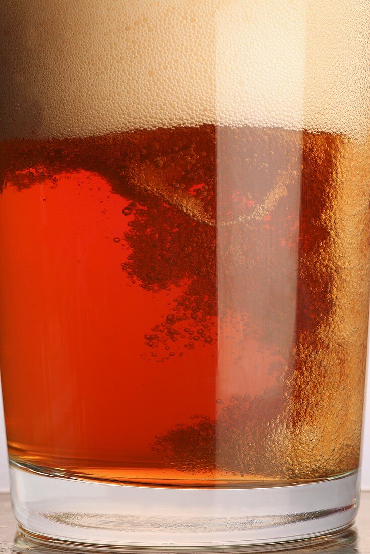 A glass of beer with a lot of head (close-up)