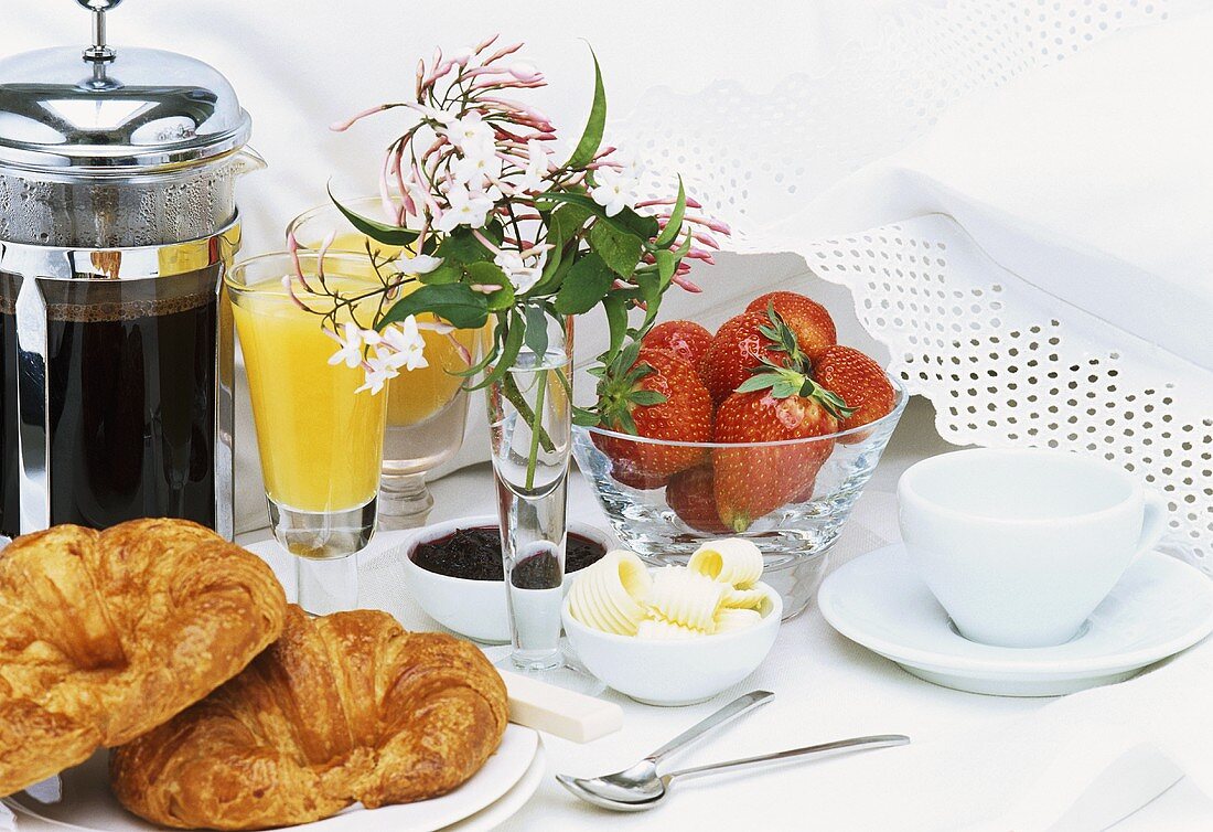Frühstück mit Croissants, Kaffee, Orangensaft und Erdbeeren