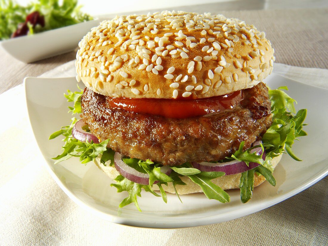 Burger mit Rucola, Zwiebeln und Ketchup im Sesambrötchen