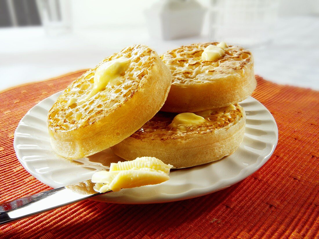 Crumpets (englische Löcher-Toasties) mit Butter auf Teller