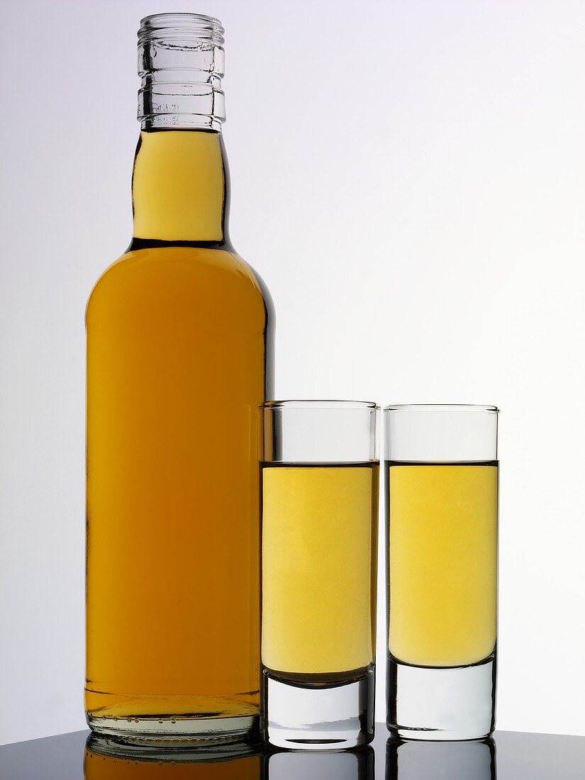 Brauner Rum in zwei Gläsern und Flasche