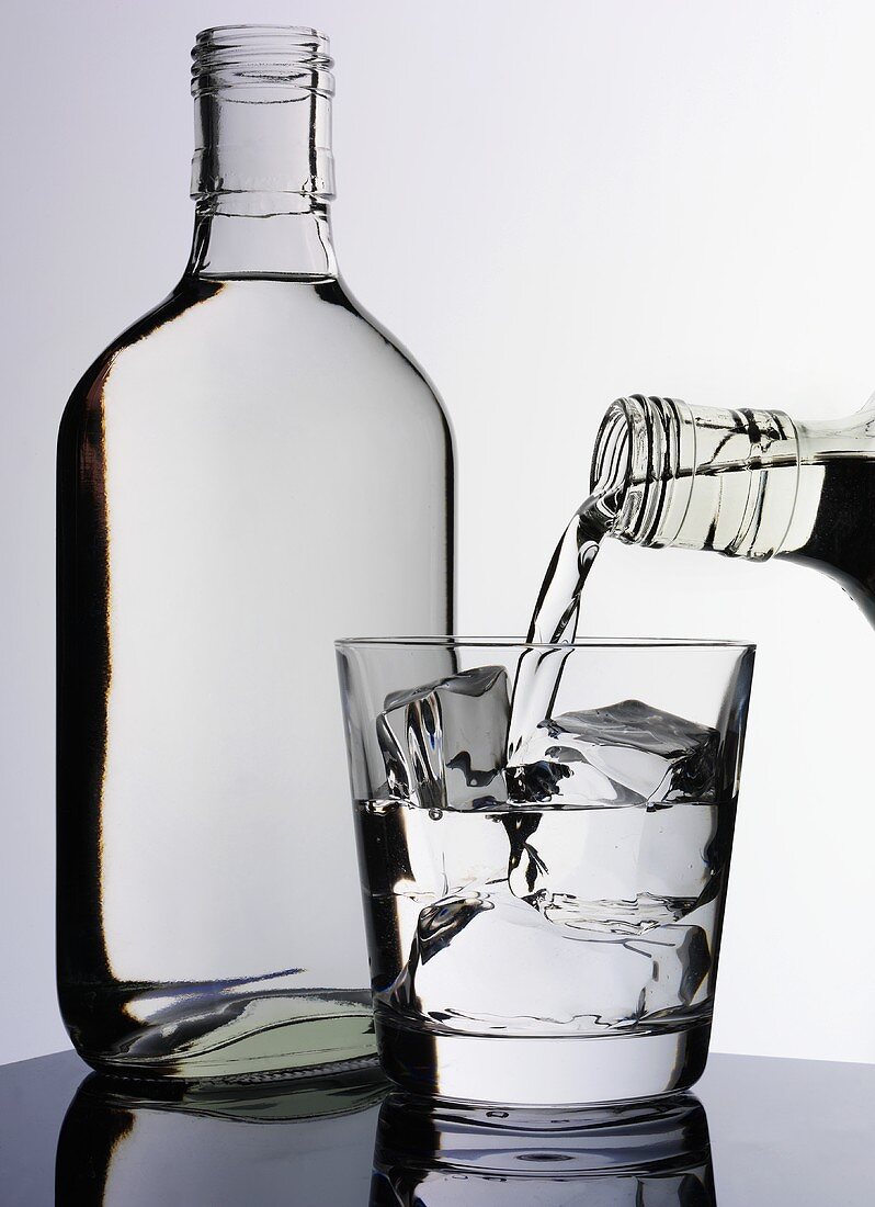 Pouring a glass of vodka, vodka bottle beside it