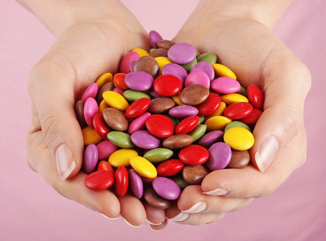 Hands holding coloured Smarties