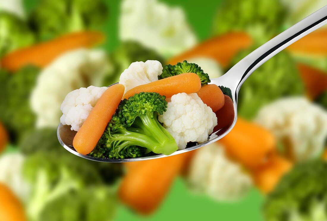 Mixed vegetables on a spoon and in background