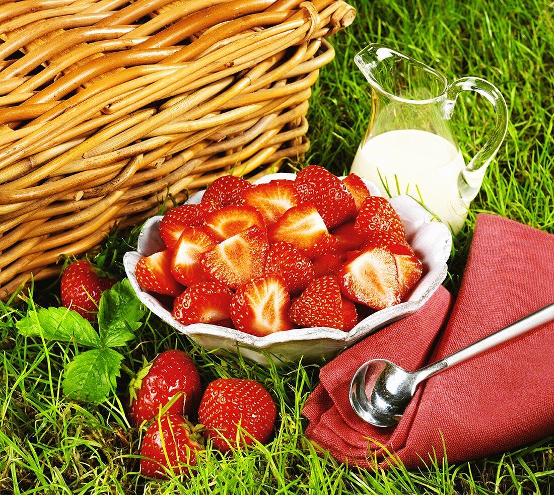 A dish of strawberries and cream in a glass jug