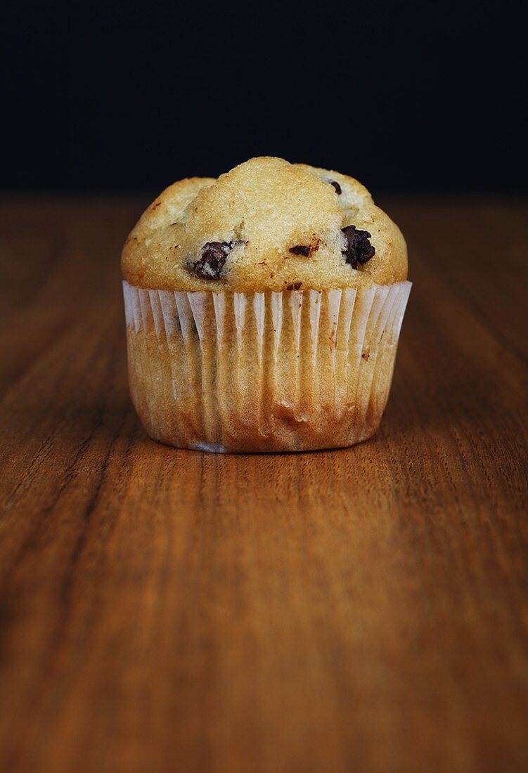 A chocolate chip muffin on wooden background