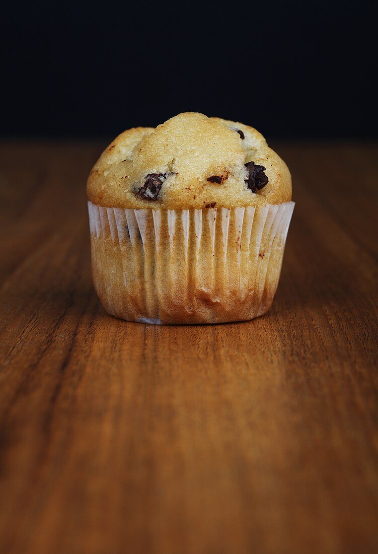 Ein Chocolate-Chip-Muffin auf Holzuntergrund