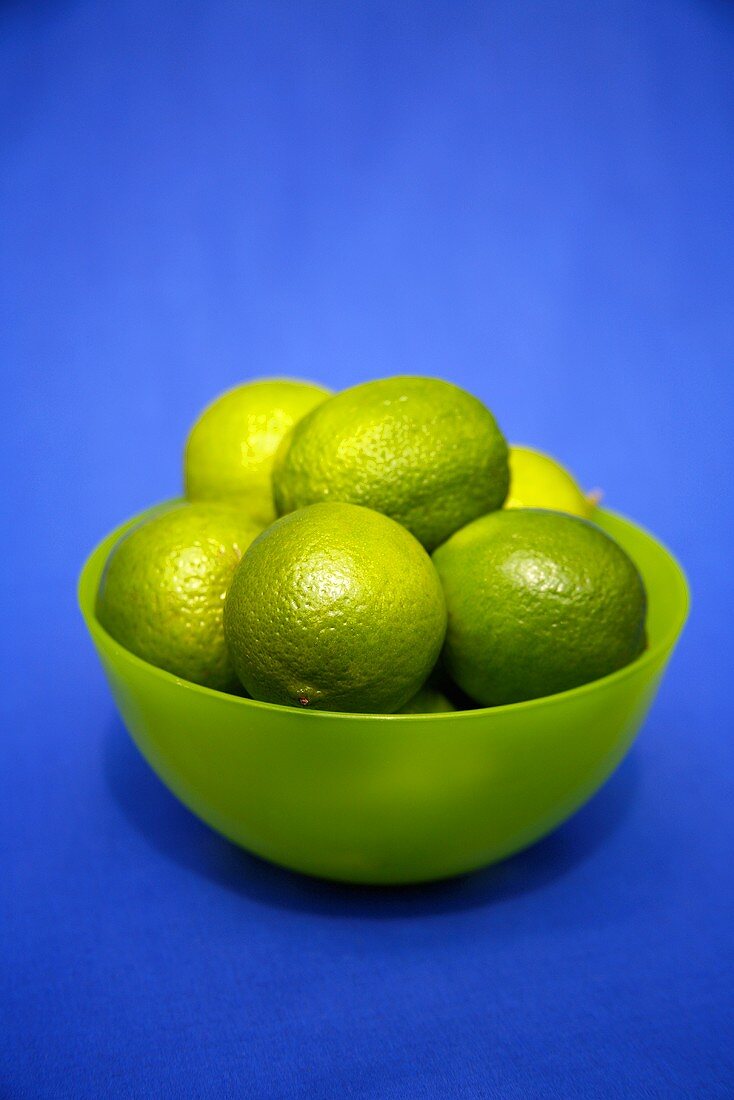 Limes in a bowl against a blue background