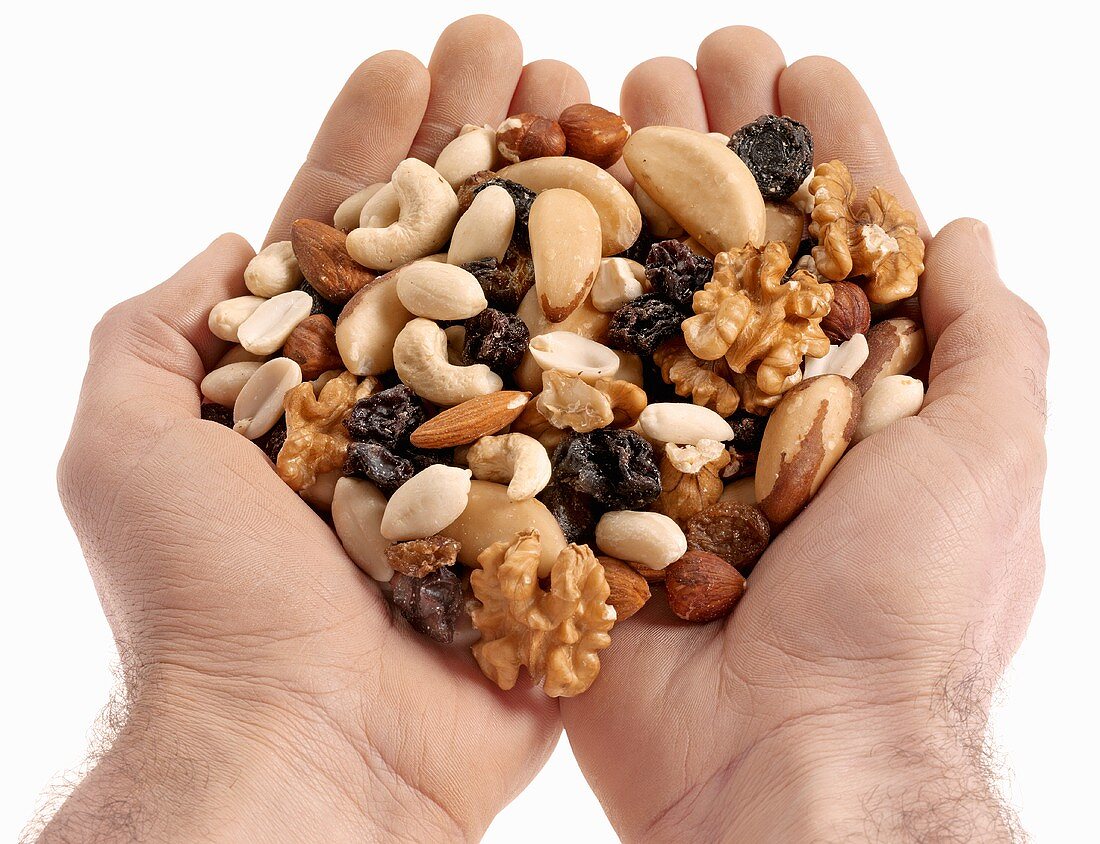 Two hands holding nuts and raisins