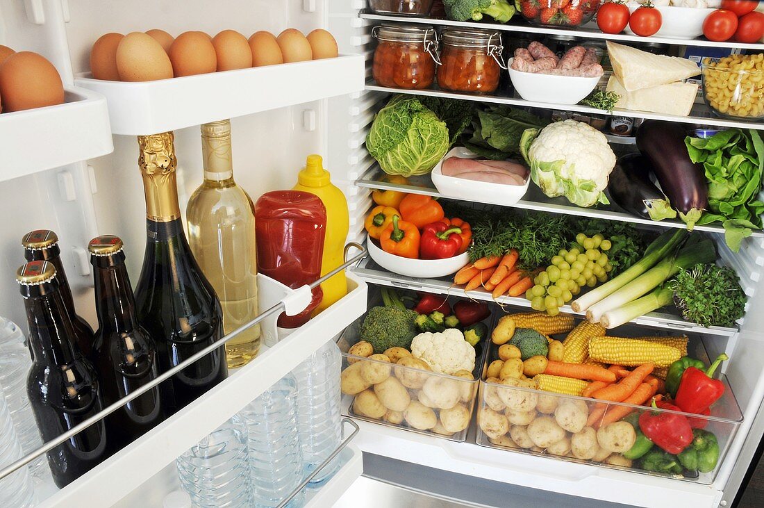 Verschiedene Lebensmittel in offenem Kühlschrank