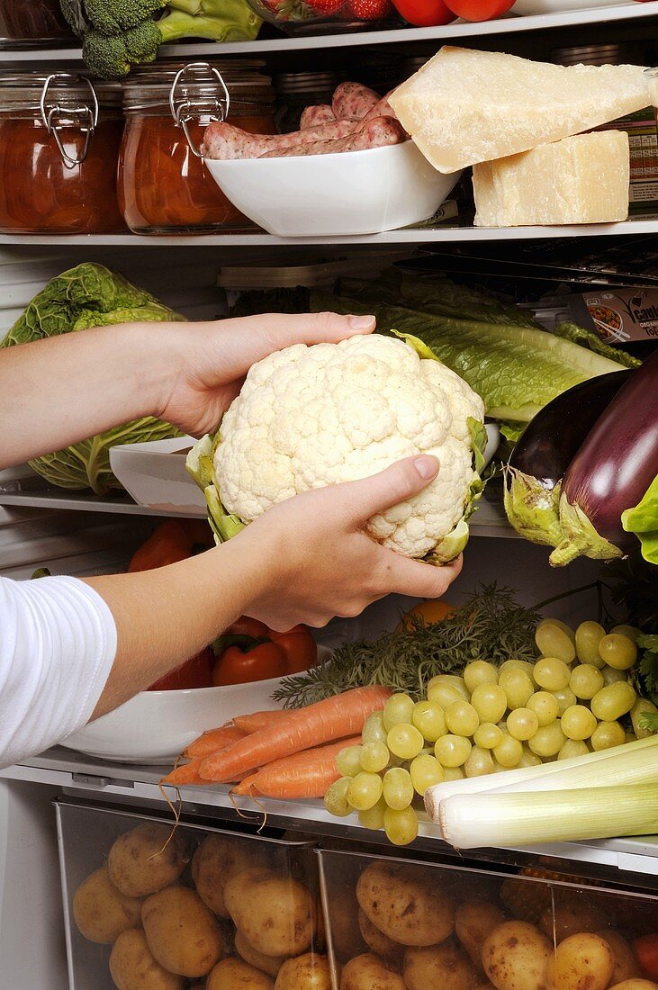 Taking a cauliflower out of a refrigerator