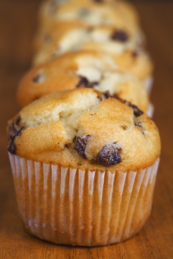 Vier Muffins in einer Reihe auf Holzuntergrund