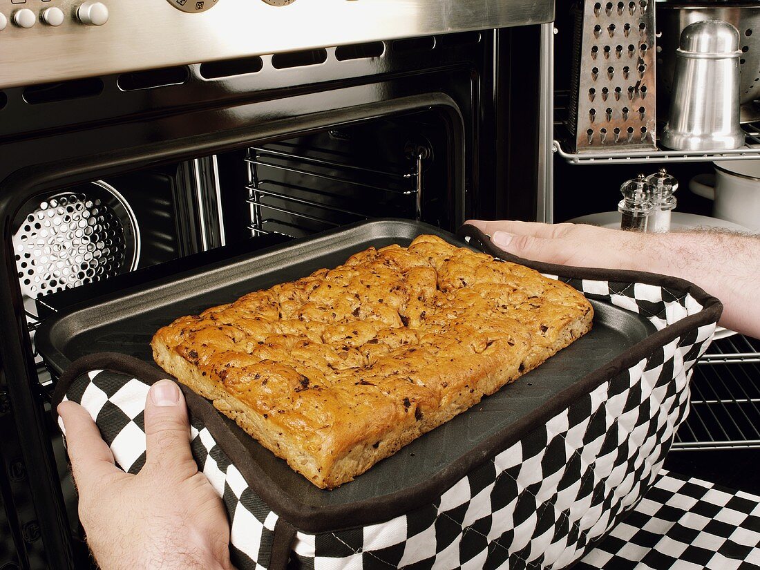 Man taking a tray of focaccia out of the oven
