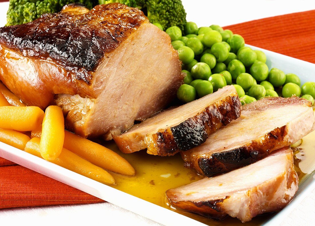 Roast ham, partly carved, with vegetables