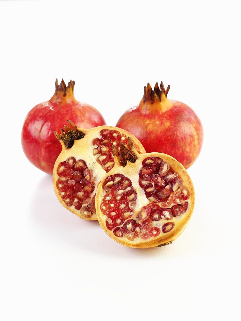 Pomegranates, two whole and one halved