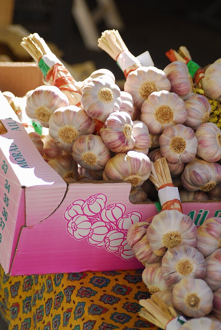 Garlic plaits in a cardboard box on a market stall