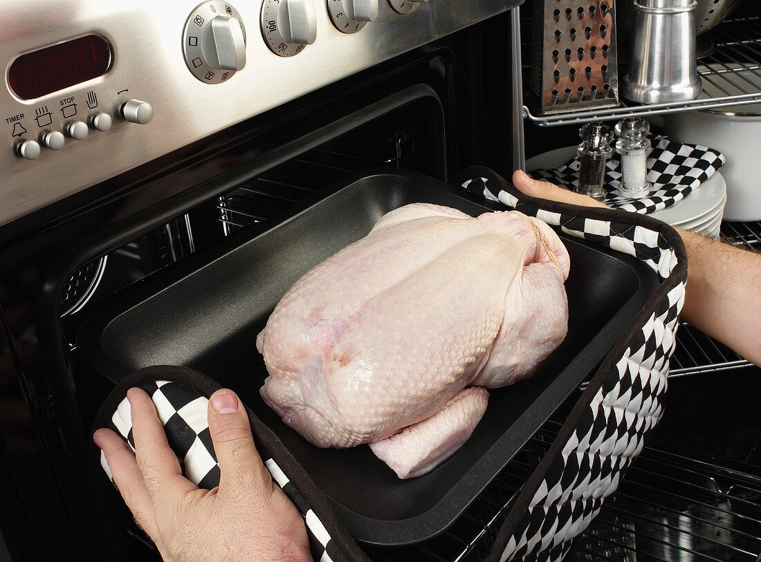 Man putting a chicken into the oven