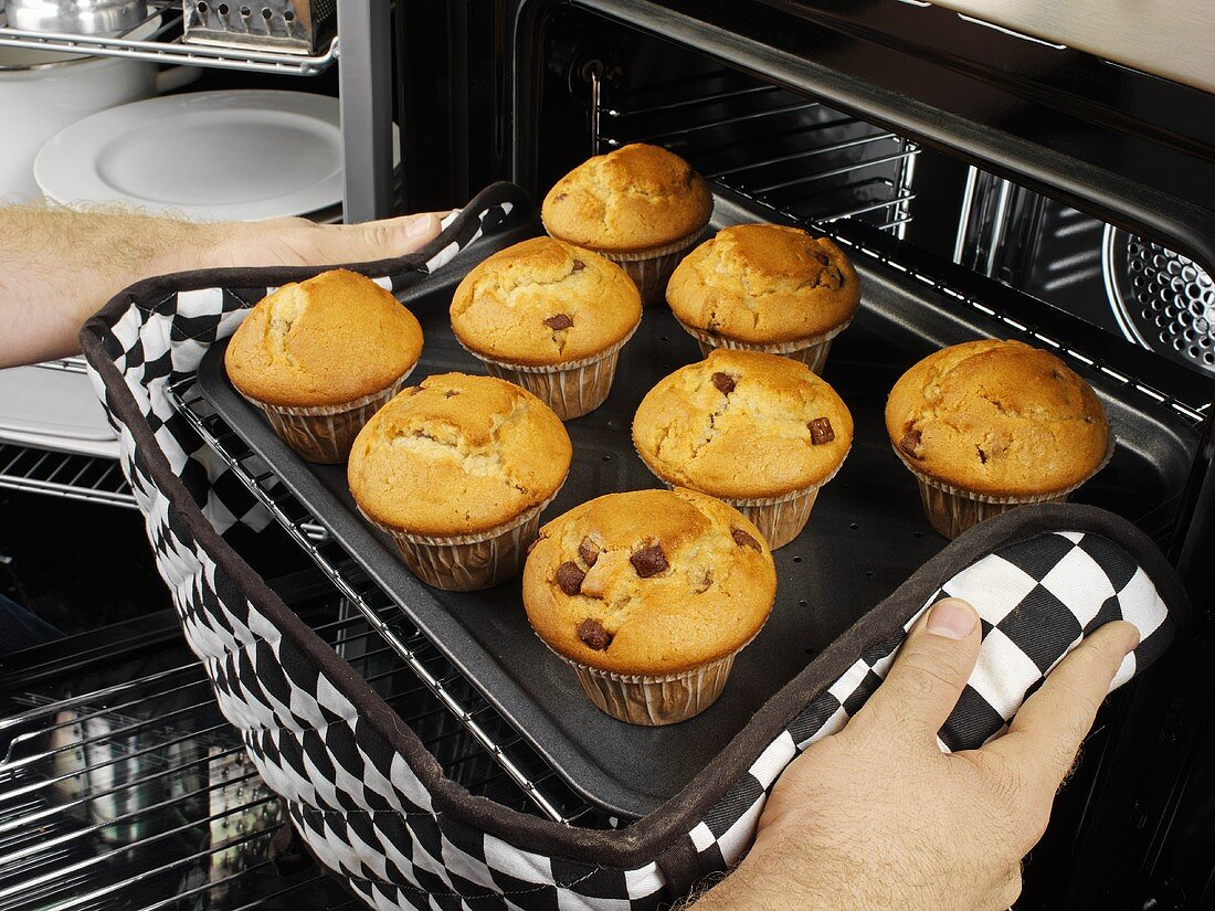 Man taking muffins out of the oven