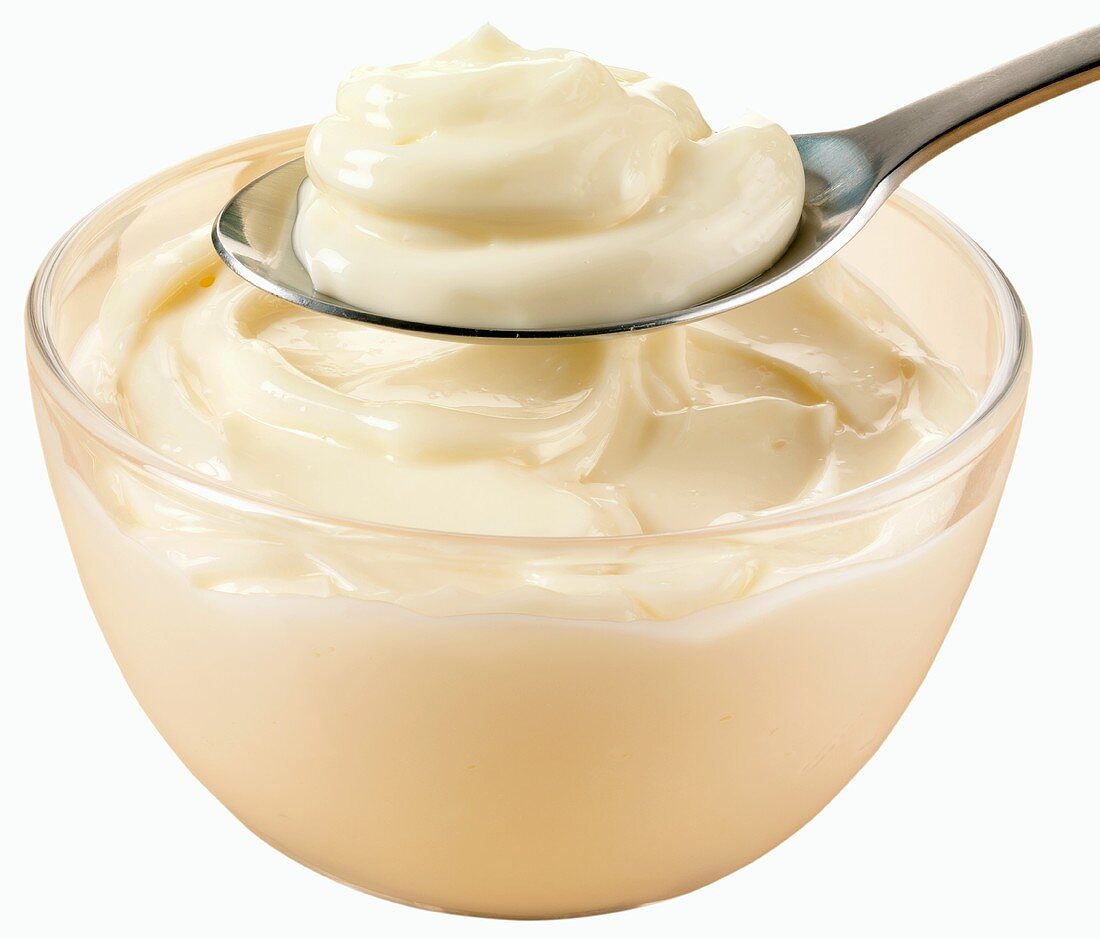 Mayonnaise in a glass bowl and on a spoon