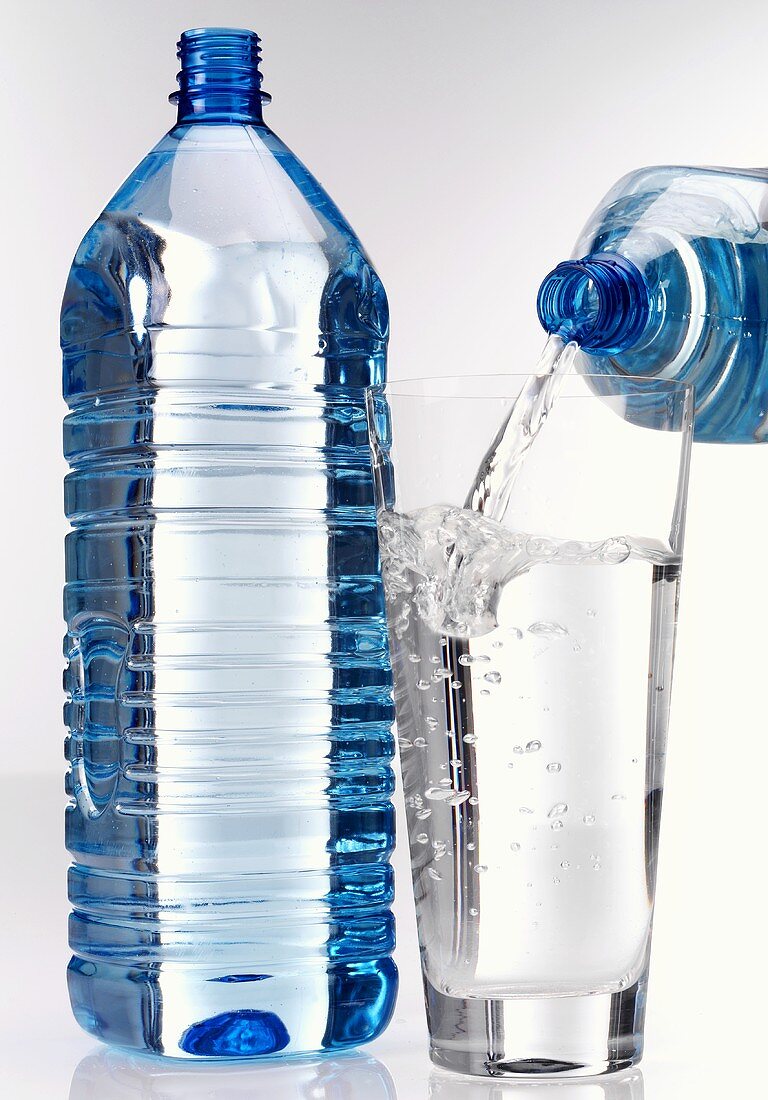 Aus einer Plastikflasche ein Glas Wasser einschenken