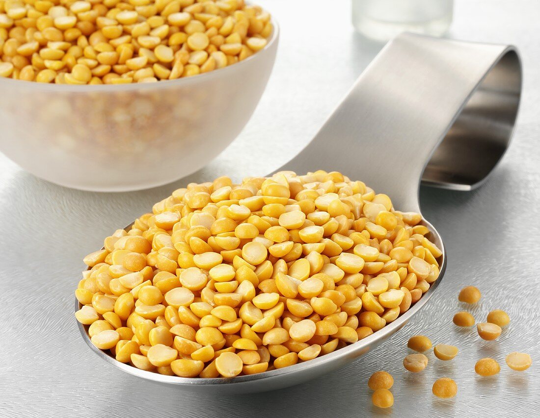 Yellow split peas on a spoon and in a glass bowl