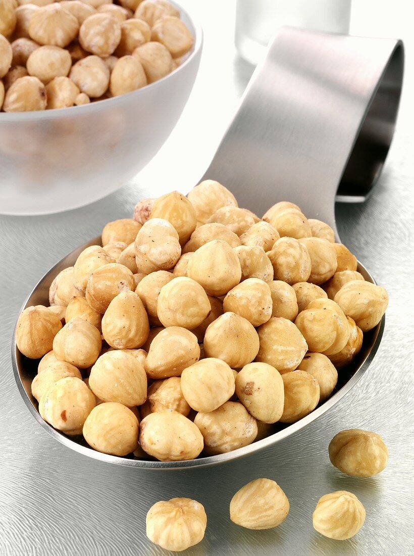Blanched hazelnuts on a spoon and in a glass bowl