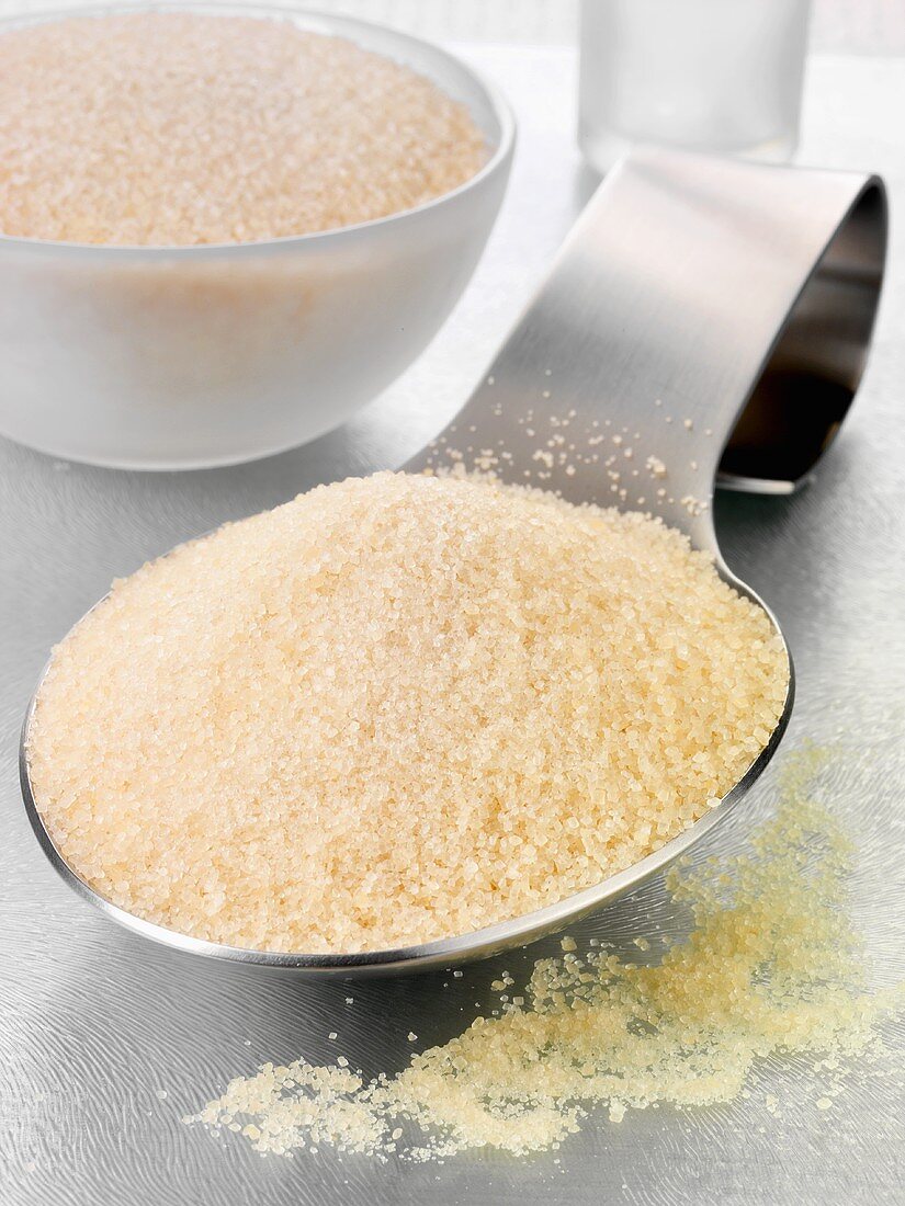 Golden sugar on a spoon and in a glass bowl
