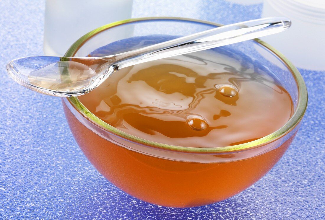Gelled chicken stock in a glass bowl with plastic spoon
