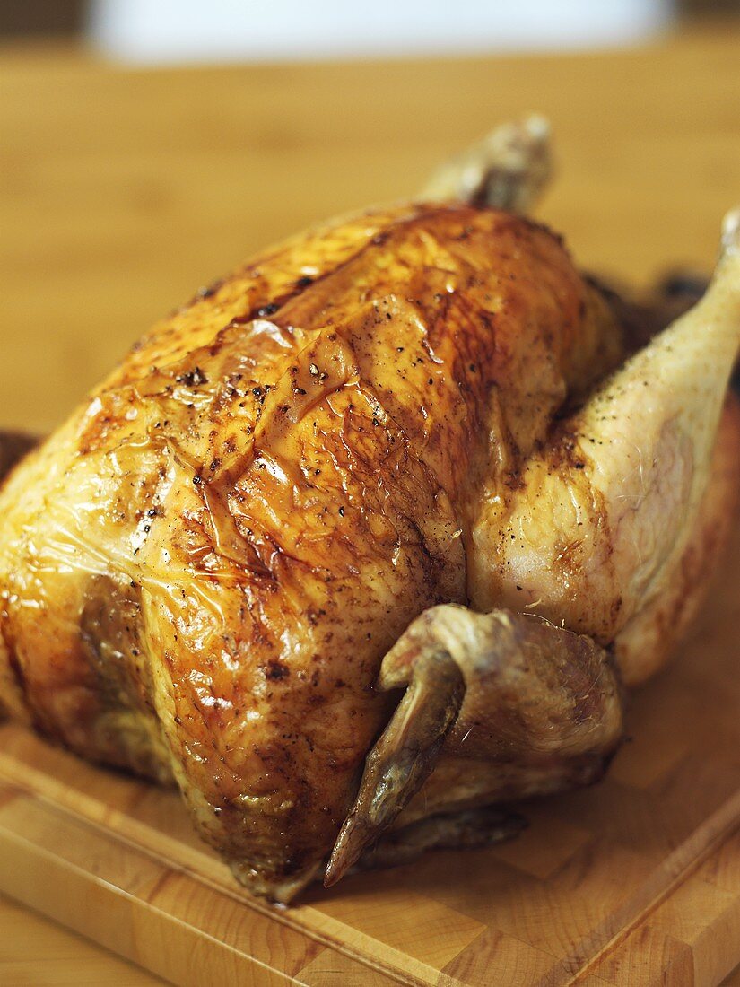 Whole roast chicken on a wooden board