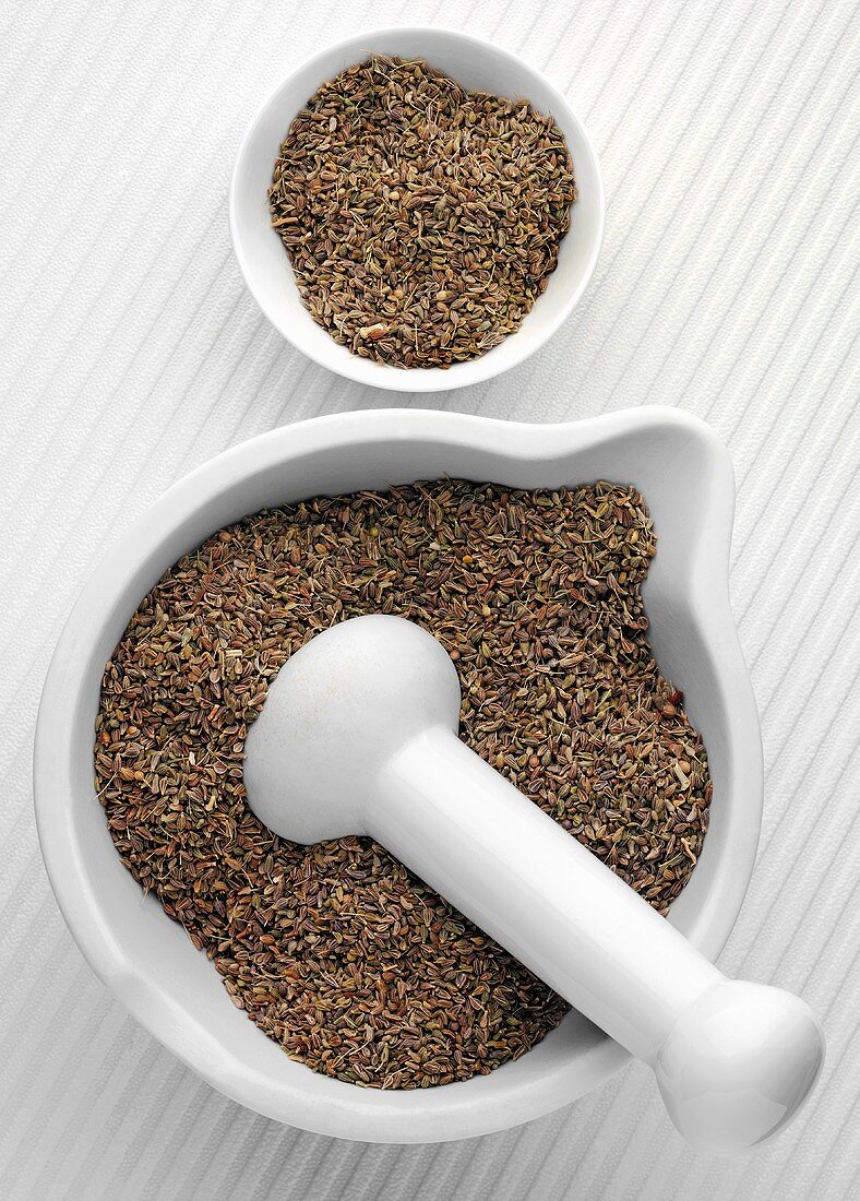 Aniseed in a mortar with pestle and a small dish