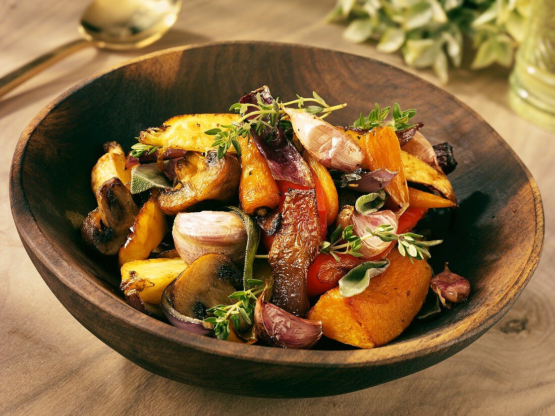 Roasted vegetables with herbs in a wooden bowl