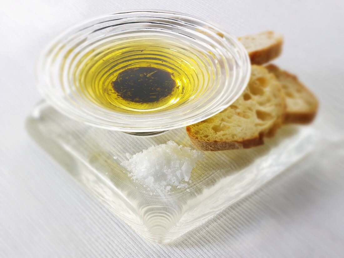 Olivenöl mit Baslamico in einem Glasschälchen mit Salz, Brot