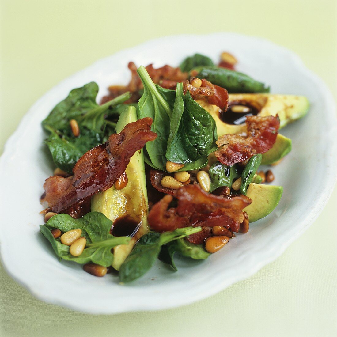 Spinach and avocado salad with fried bacon and pine nuts