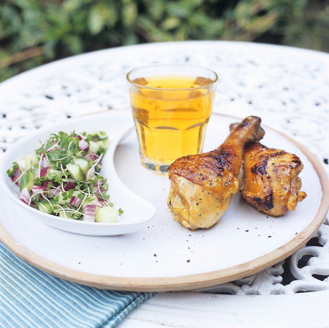 Hähnchenkeulen mit Gurkensalat im Freien