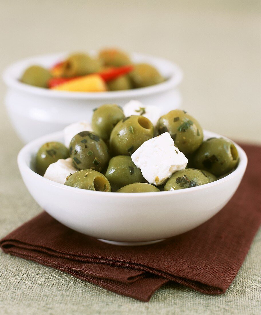 Two small dishes of olives, feta and peppers
