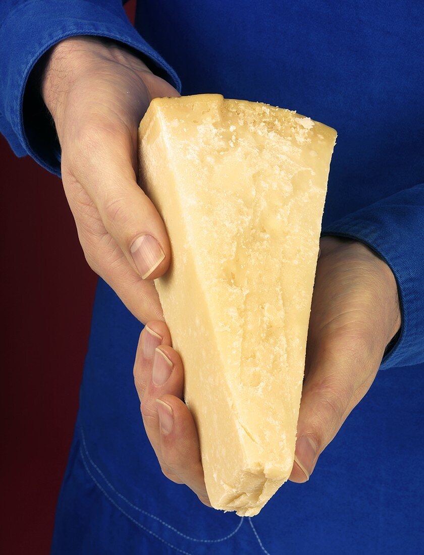 Hands holding a piece of Parmesan